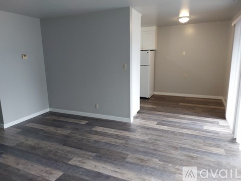 A room with a carpeted floor and a white refrigerator.