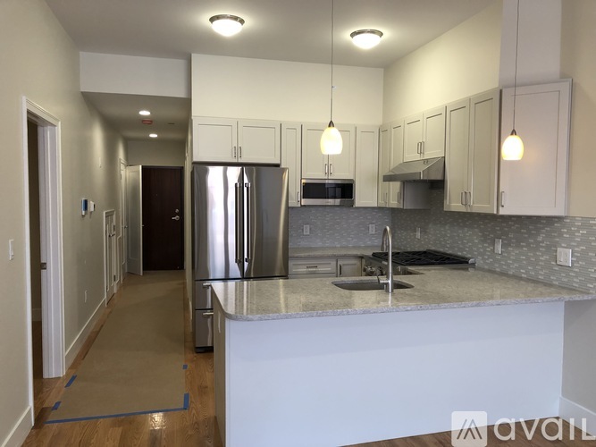 A kitchen with a refrigerator, sink, and cabinets.