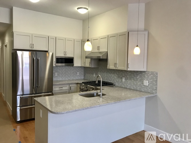 A kitchen with a stainless steel refrigerator and a marble countertop.
