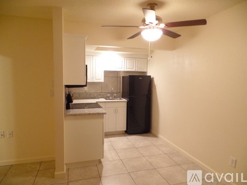 A kitchen with a black refrigerator and white cabinets.