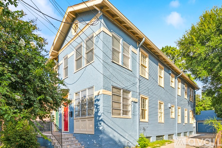 A blue house with a white window and a black railing.