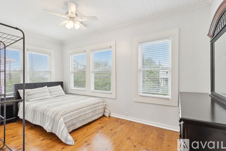 A bedroom with a bed, a ceiling fan, and a window with blinds.