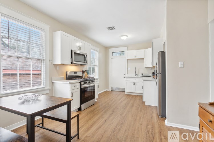 A kitchen with white cabinets and a wooden floor.