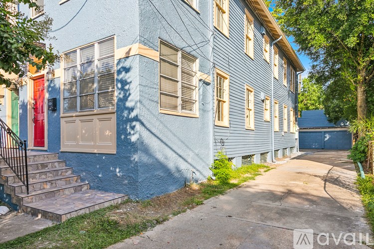 A blue house with a red door and a tree in front.