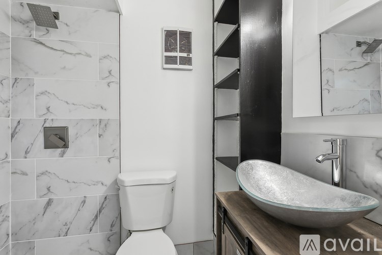 A bathroom with a marble tile shower and a white toilet.
