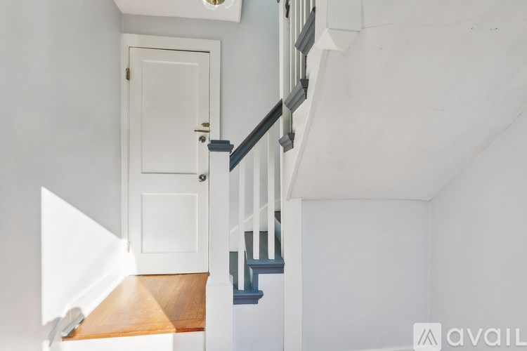 A white door is on the left side of a staircase.