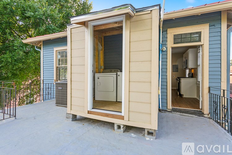 A small house with a blue exterior and a wooden exterior with a window and a door open.