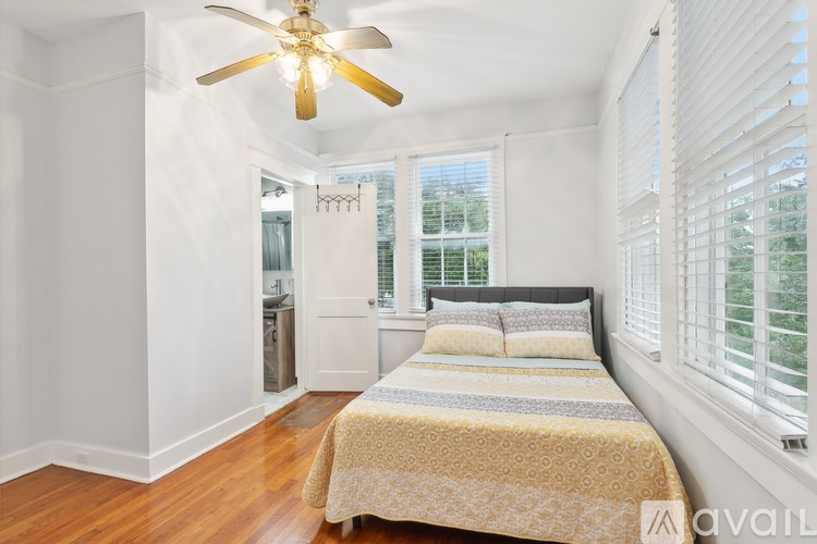 A bedroom with a bed, a ceiling fan, and a window with blinds.