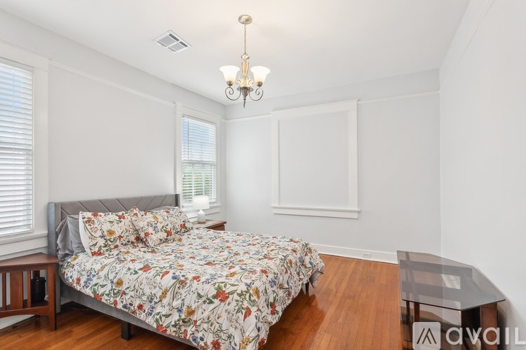 A bedroom with a floral bedspread and a chandelier.