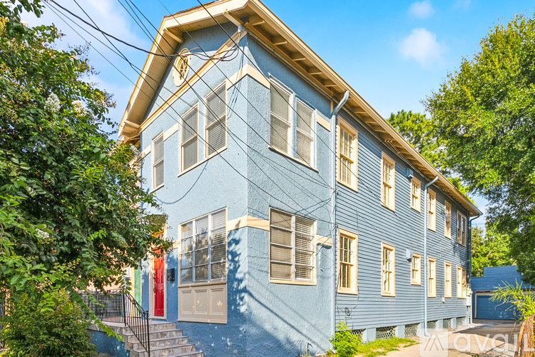 A blue house with a white trim and a red door.
