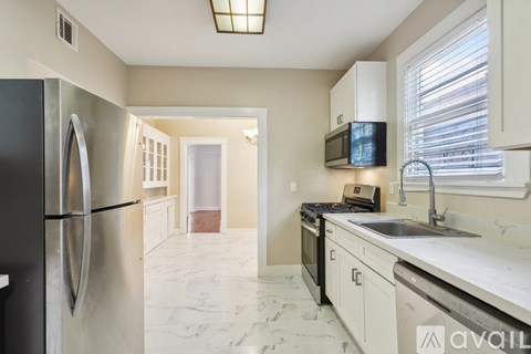 A kitchen with a refrigerator, microwave, oven, and sink.