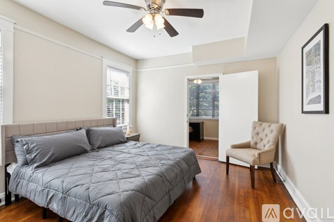 A bedroom with a bed, chair, and ceiling fan.
