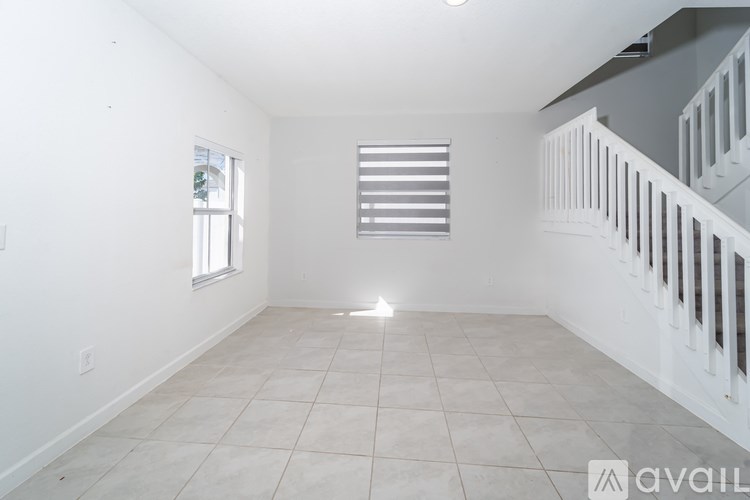 A spacious room with a window and a staircase.