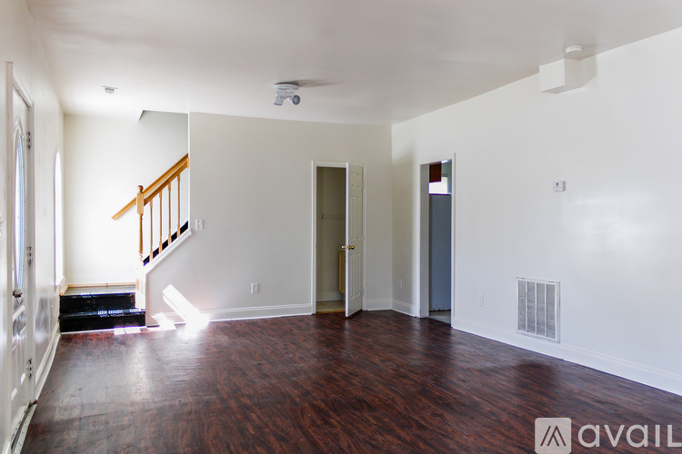 A room with wooden floors and white walls is available for rent.