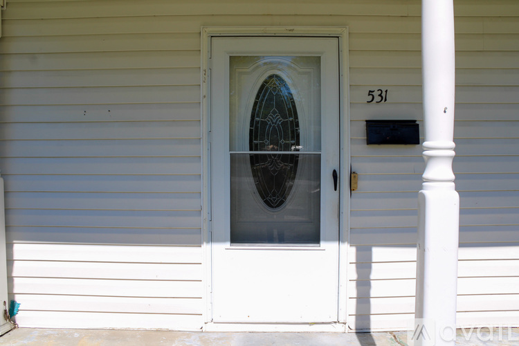 A white door with a glass window and a mailbox on the side of a house.