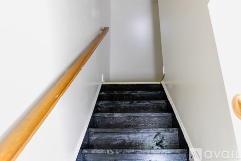 A staircase with a wooden handrail and black steps.