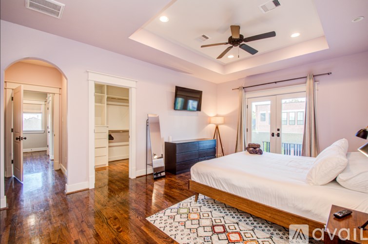 A bedroom with a bed, a television, and a ceiling fan.