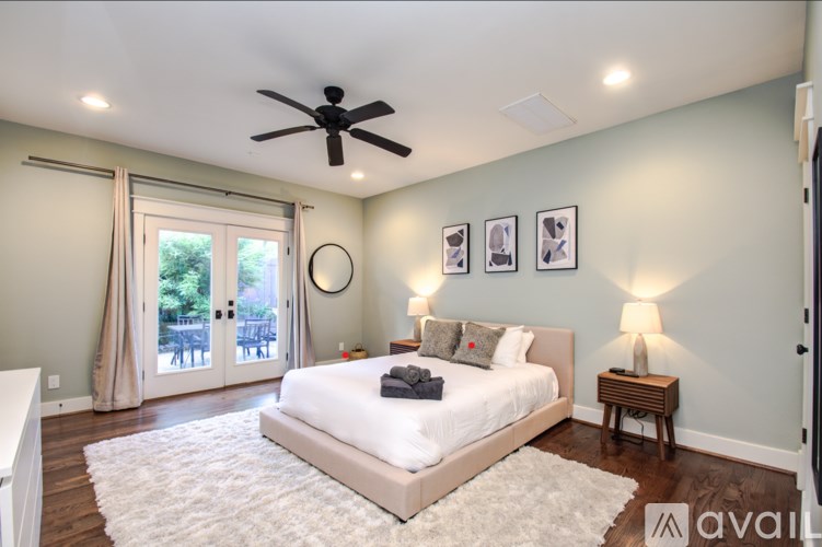 A bedroom with a large bed, a ceiling fan, and a sliding glass door.