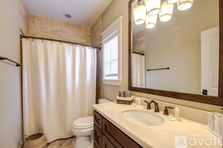 A bathroom with a toilet, sink, mirror, and shower curtain.