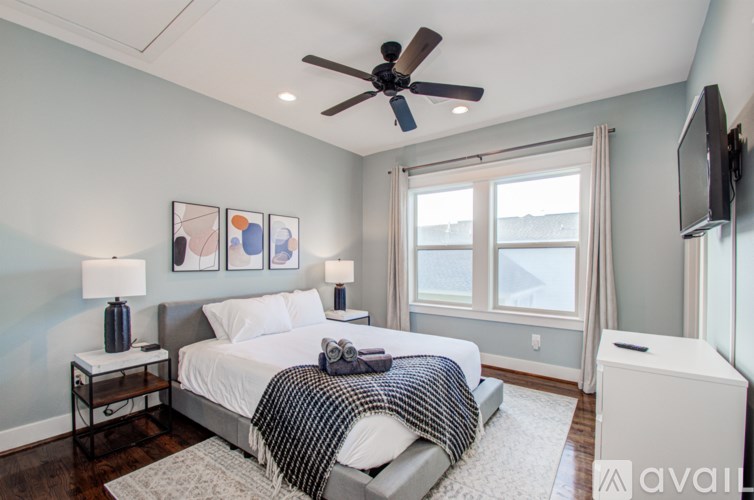 A bedroom with a bed, a ceiling fan, and a television.