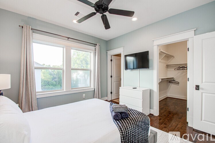 A bedroom with a large bed and a ceiling fan.
