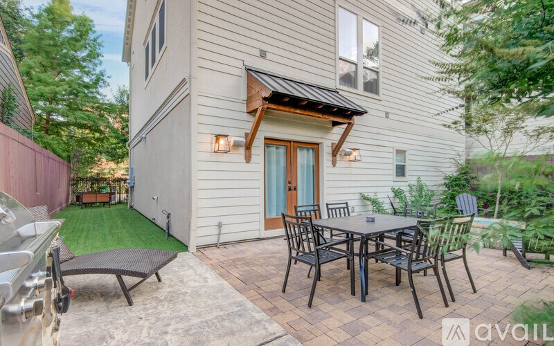 A patio with a table and chairs is in front of a house.