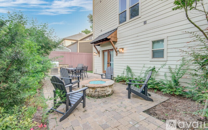 A patio with a table and chairs is surrounded by green plants.