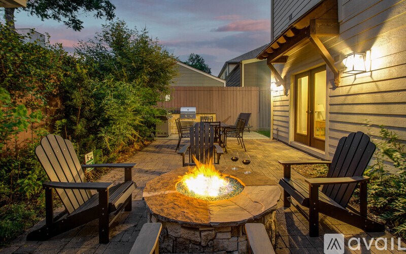 A backyard with a fire pit surrounded by chairs and a house.