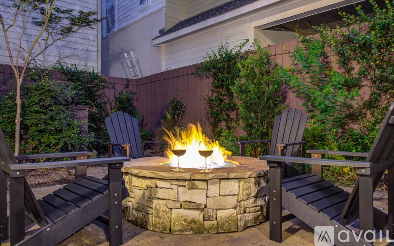 A fire pit in the middle of a backyard with two chairs on either side.
