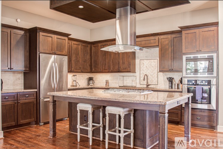 A kitchen with a large island and a stainless steel refrigerator.