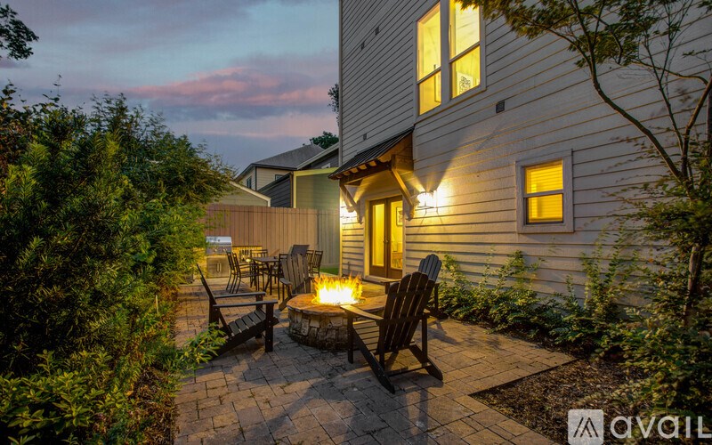 A patio with a fire pit and chairs is in front of a house.