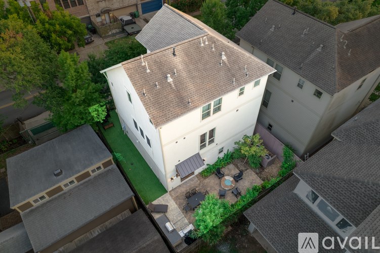 A house with a white exterior and a brown roof is surrounded by other houses.