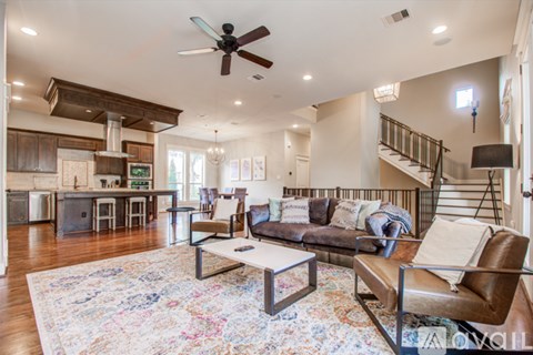 A living room with a brown couch and a rug.