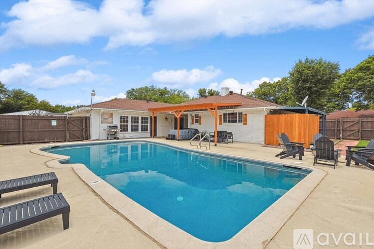 A pool with a bench and a house in the background.