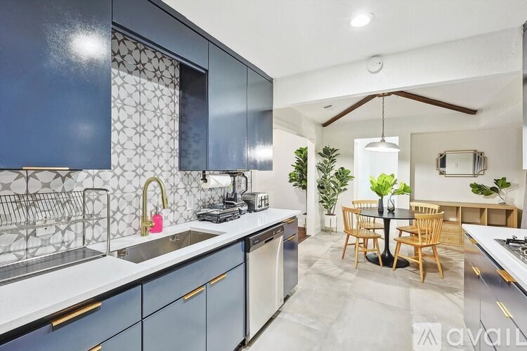 A kitchen with dark blue cabinets and a white backsplash.