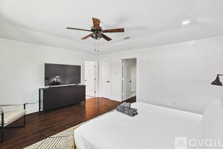 A bedroom with a bed, a dresser, a chair, and a ceiling fan.