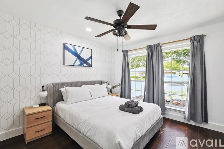 A bedroom with a bed, nightstand, and a ceiling fan.