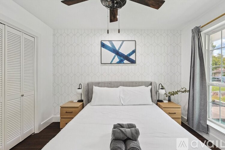 A bedroom with a large bed, a ceiling fan, and a window with a view of the outside.