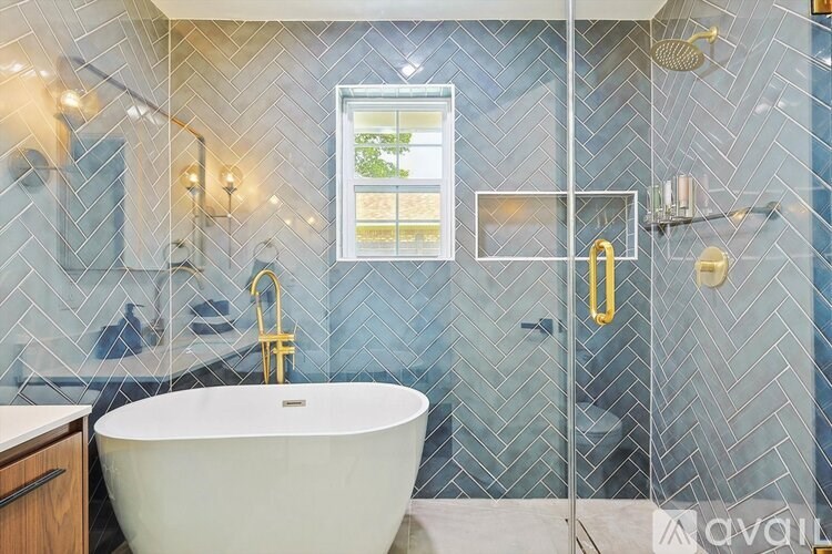 A modern bathroom with a white bathtub and a glass shower enclosure.