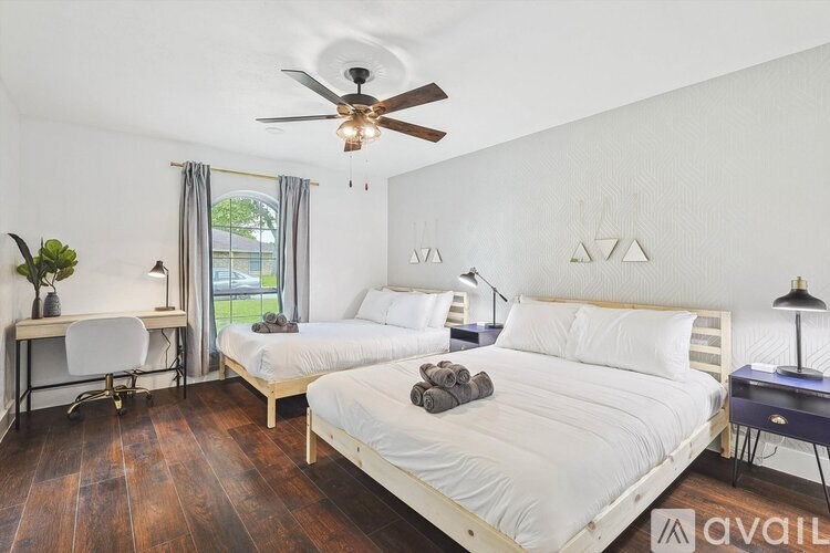 A bedroom with two beds, a desk, and a ceiling fan.