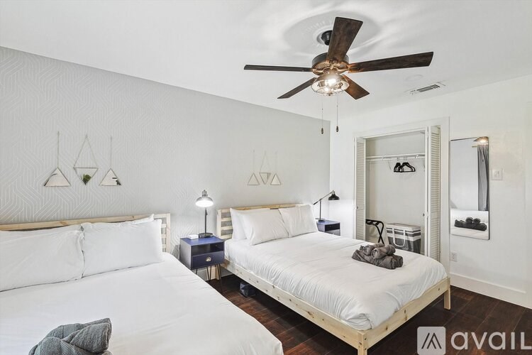 A bedroom with two beds, a ceiling fan, and a mirror.