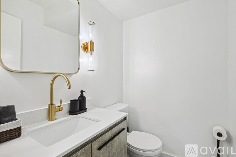A bathroom with a white toilet, a sink with a gold faucet, and a mirror above it.