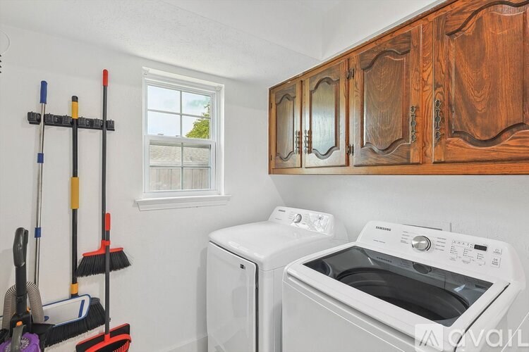 A laundry room with a washer and dryer, a window, and a rack of cleaning supplies.