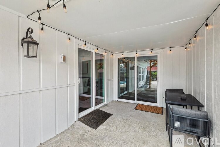 A patio area with a table and chairs and string lights.