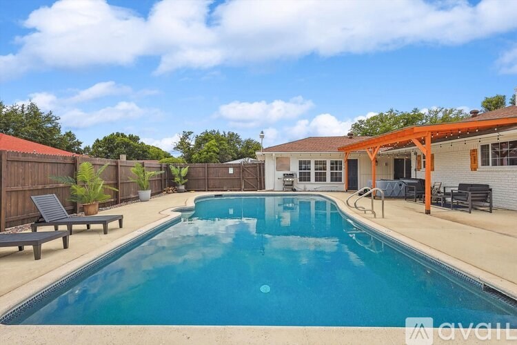 A pool in a backyard with a wooden fence and a bench.