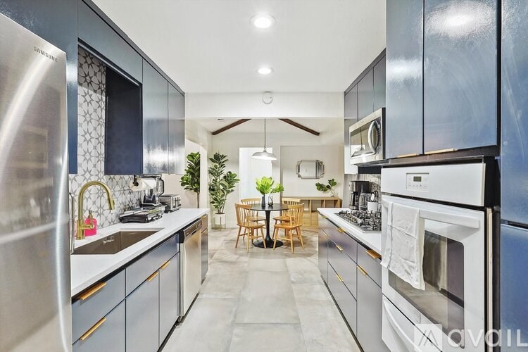 A modern kitchen with stainless steel appliances and a dining area with a table and chairs.