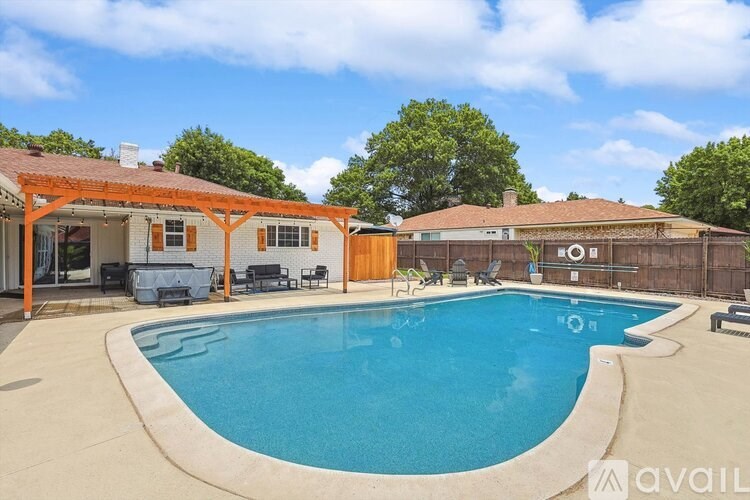 A pool in a backyard with a patio and a hot tub.