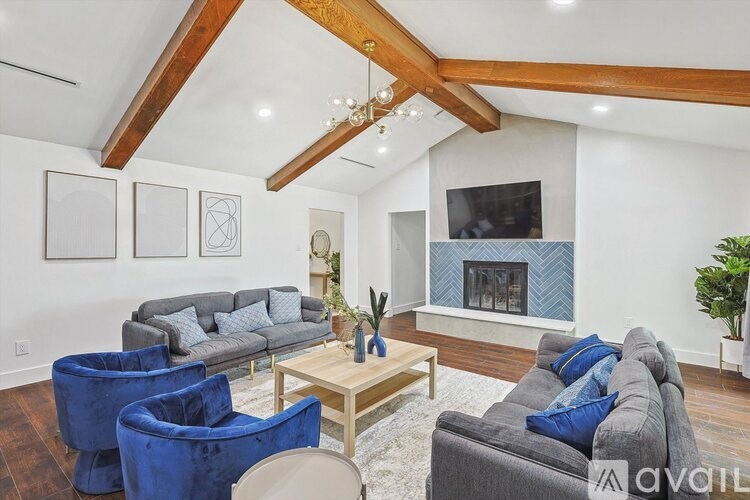 A living room with a grey couch, blue chairs and a wooden coffee table.
