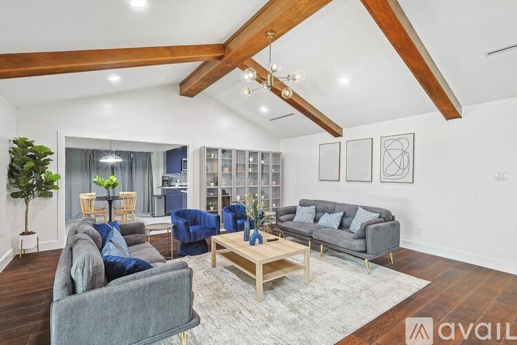 A living room with a grey couch, a blue chair, and a wooden coffee table.