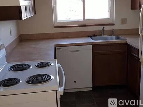 A kitchen with a white stove top oven and a white dishwasher.